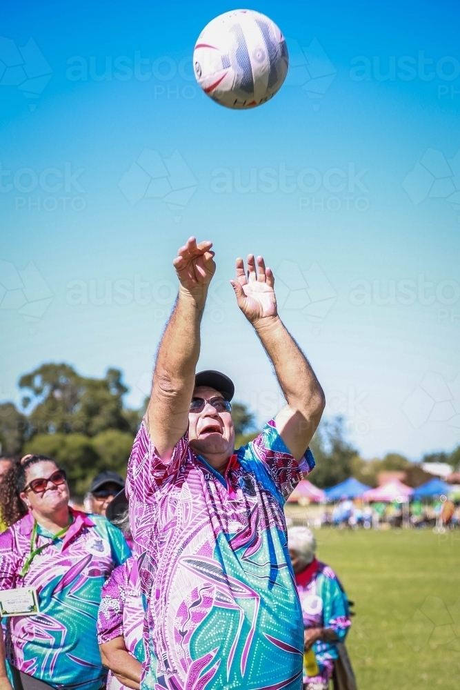 Aboriginal man throwing netball in air - Australian Stock Image