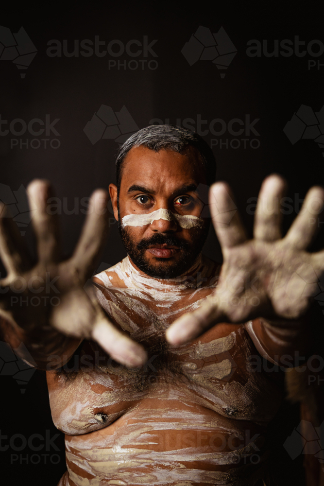 Aboriginal man with body paint extending his palms in front - Australian Stock Image
