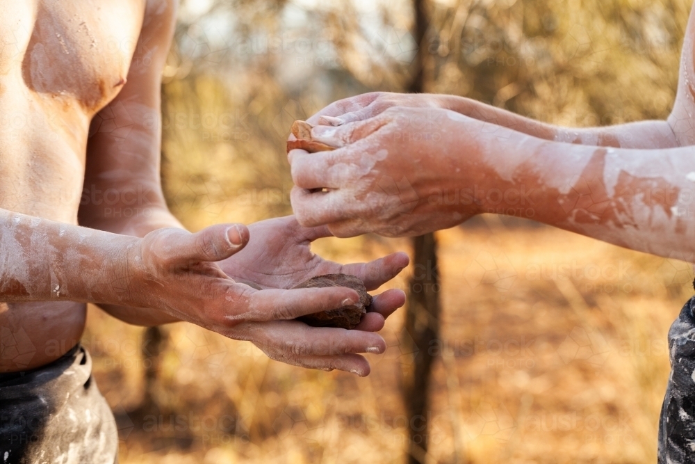 Aboriginal men holding rocks and passing them to one another - Australian Stock Image