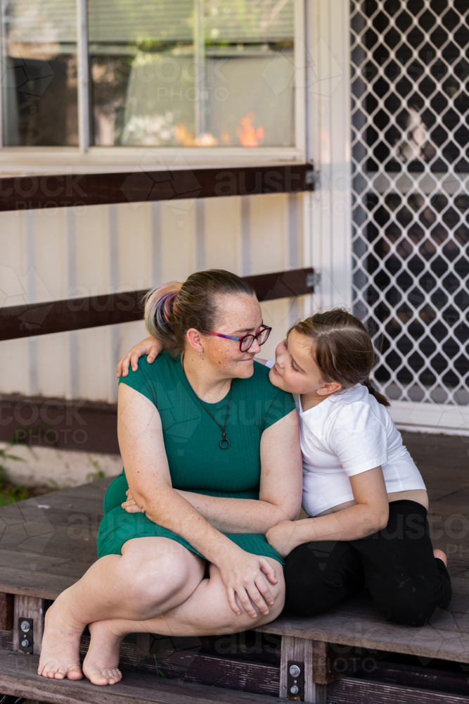 Aboriginal mother and daughter together on front stairs of their home - Australian Stock Image