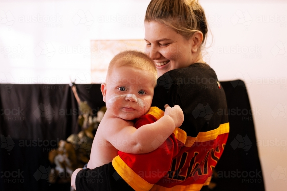 Aboriginal mother holding baby boy with ochre face paint - Australian Stock Image