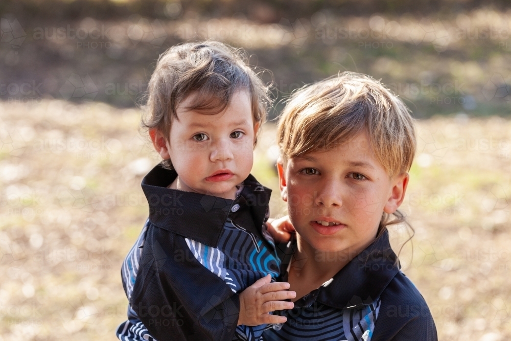 Aboriginal siblings with brother holding baby sister outside - Australian Stock Image