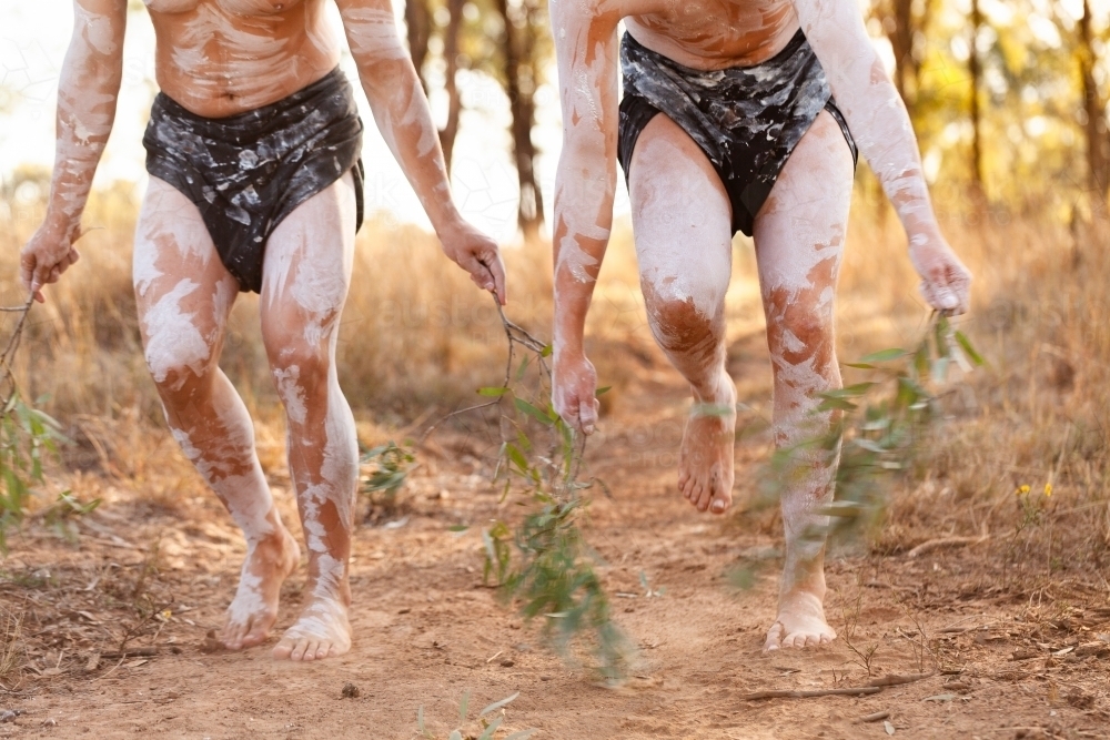 Aboriginal storytelling dance with gum leaves in dancers hands flicking up soft dust on country - Australian Stock Image