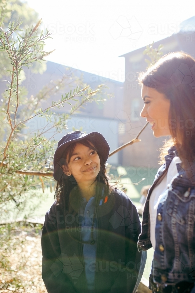 Aboriginal teacher talking to her female student outside in the school playground - Australian Stock Image