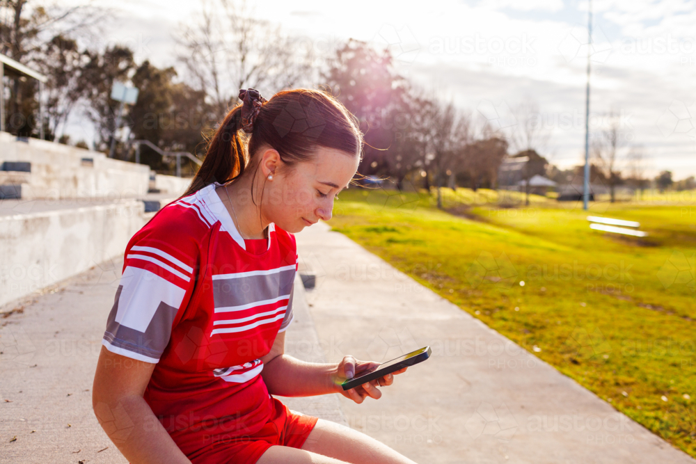 aboriginal teen girl football player using mobile phone device - Australian Stock Image