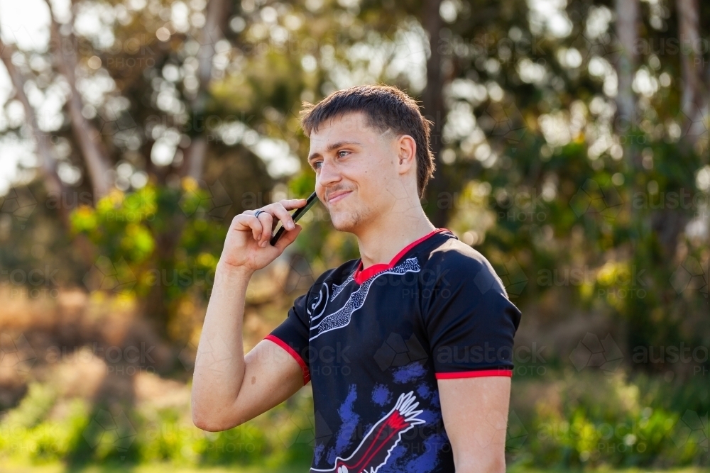 Aboriginal teenager using mobile phone to talk with mates - Australian Stock Image