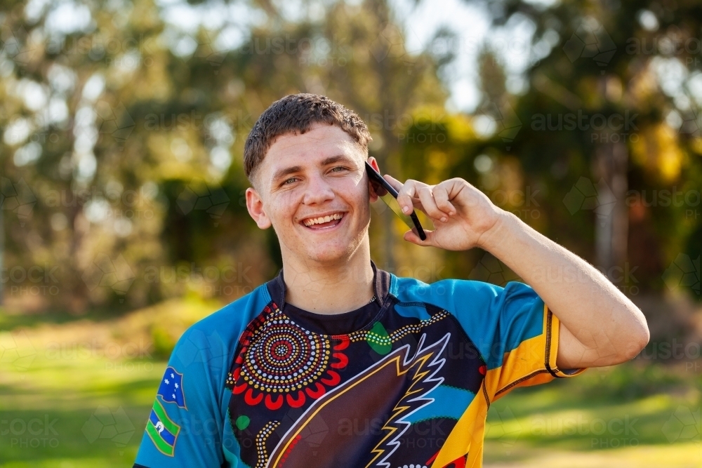 Aboriginal teenager using mobile phone to talk with mates - Australian Stock Image