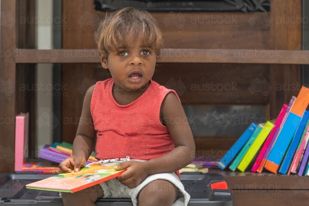 Aboriginal Toddler reading books - Australian Stock Image