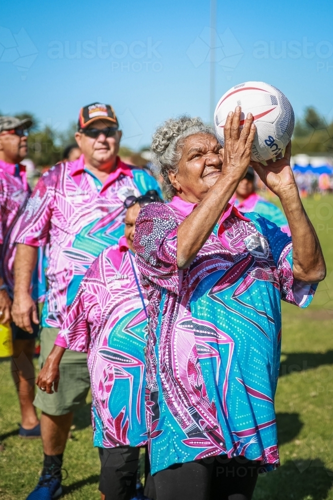 Aboriginal woman at front of line throwing a netball - Australian Stock Image