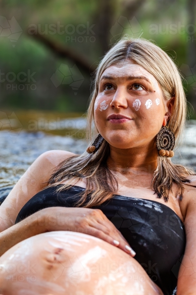 Aboriginal woman relaxing in flowing water of waterfall - Australian Stock Image