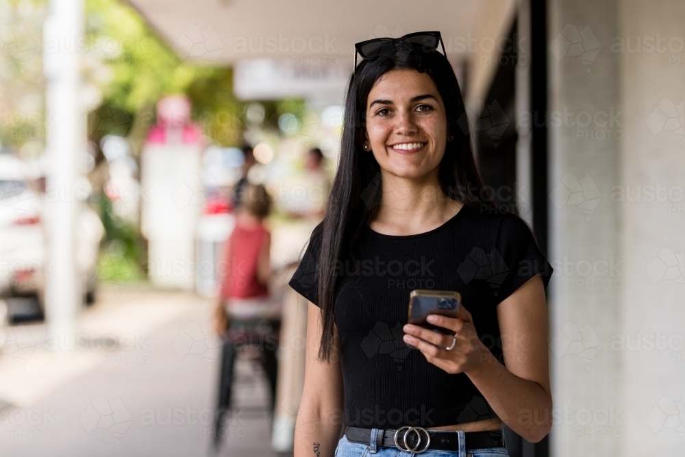 aboriginal woman walking in an urban setting, using mobile phone - Australian Stock Image