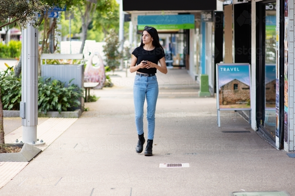 aboriginal woman walking on the footpath in an urban area - Australian Stock Image