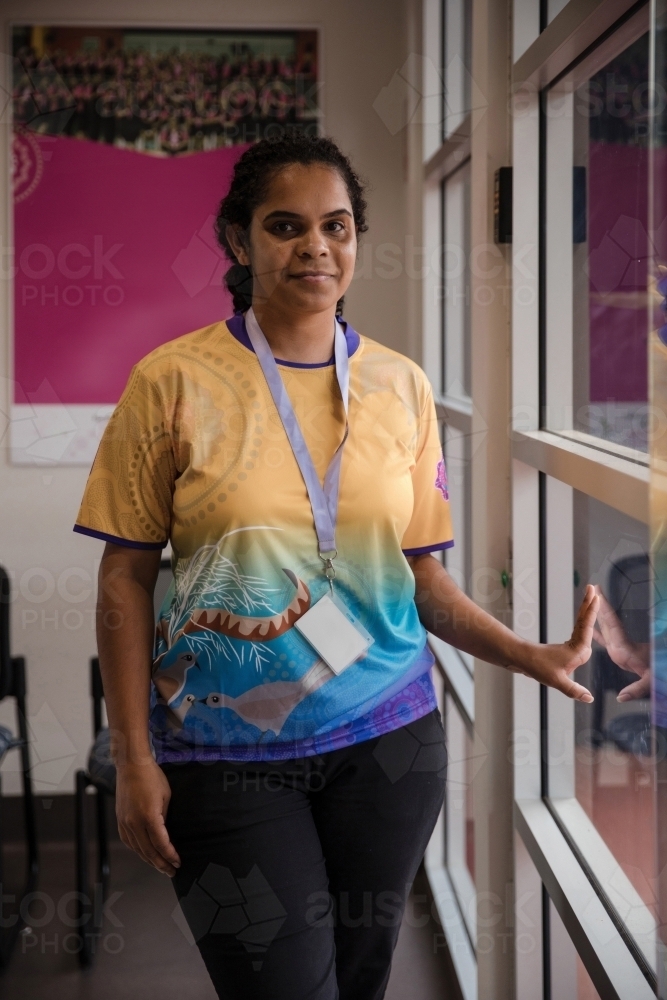 Aboriginal woman wearing lanyard beside window - Australian Stock Image