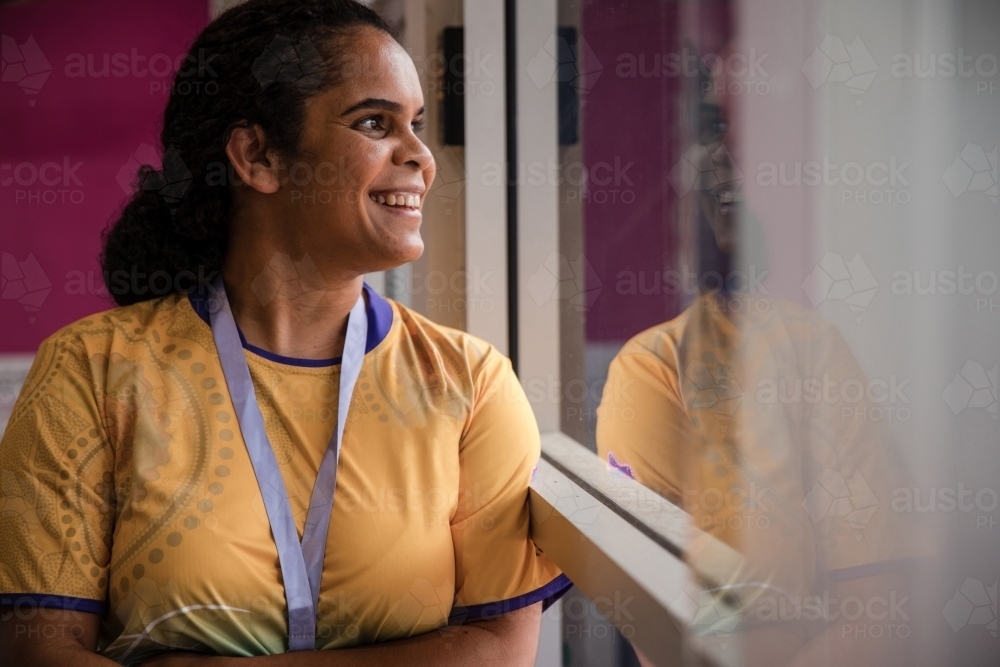 Aboriginal woman wearing lanyard looking out window - Australian Stock Image