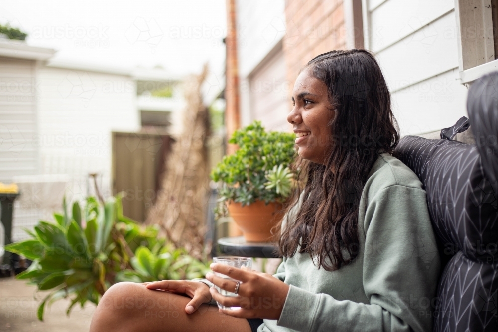 Aboriginal young woman holding glass of drinking water outside - Australian Stock Image