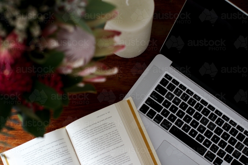 Above angle close up of corner of book and laptop keyboard on a desk - Australian Stock Image