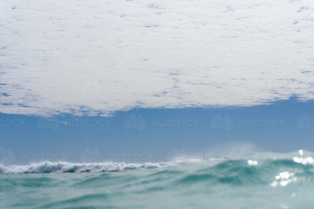 Abstract shot of surface of ocean with whitewash and blue skies in the background - Australian Stock Image