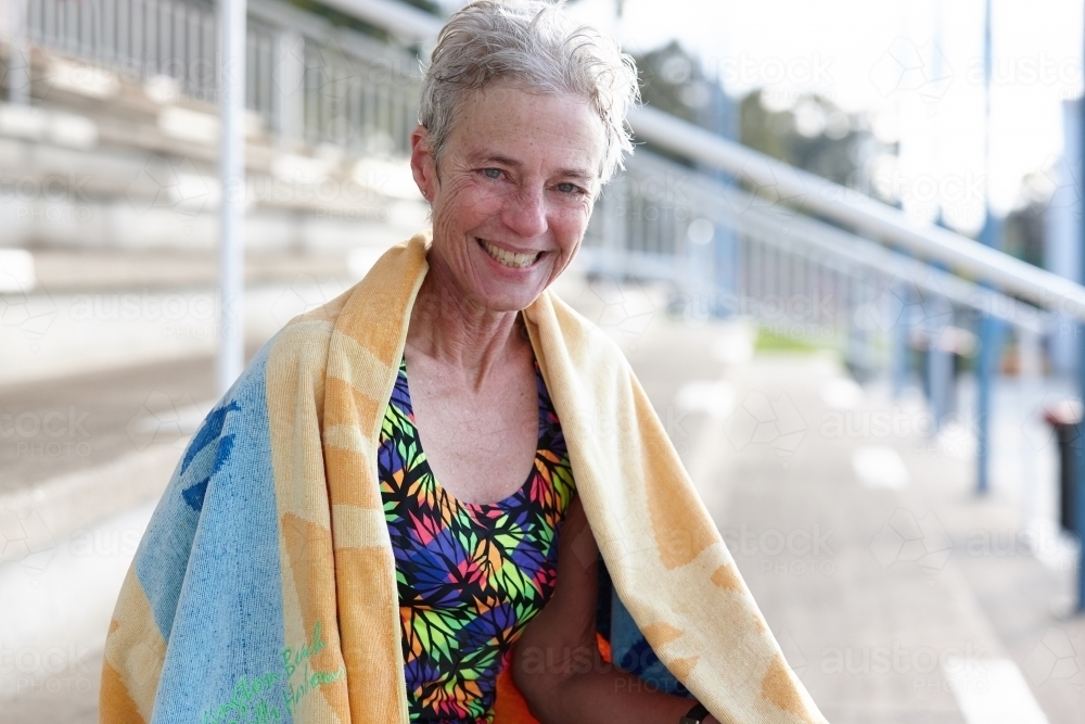 Active senior lady laughing with towel at swimming pool - Australian Stock Image