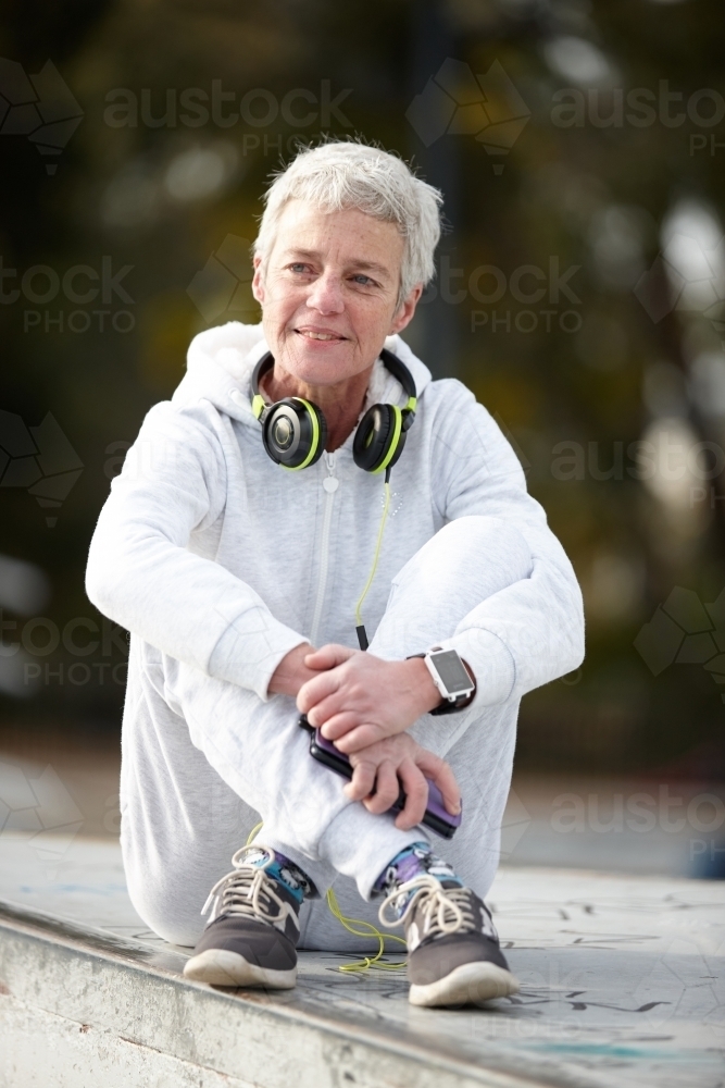 Active senior lady listening to music with headphones - Australian Stock Image