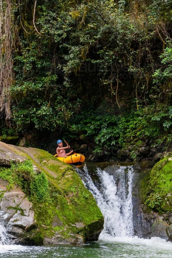 Adventurous Australian man rafting down a waterfall in NSW Australia - Australian Stock Image