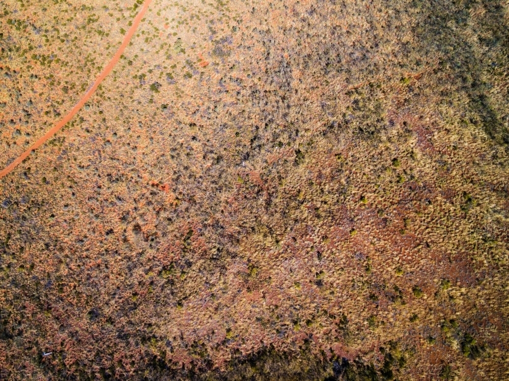 Aerial of dirt road through scrubby landscape - Australian Stock Image