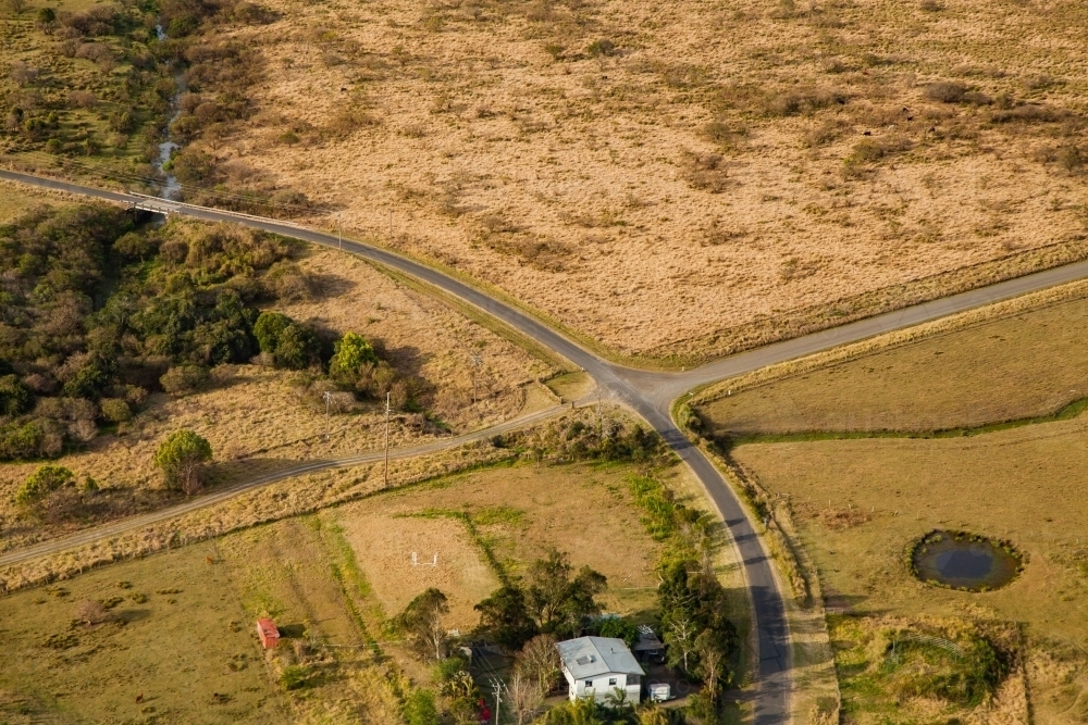 Aerial of intersection of country roads with dam and farm house - Australian Stock Image