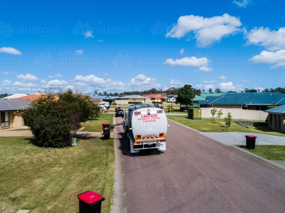 Aerial photo of a garbage truck emptying waste bins along suburban street - Australian Stock Image