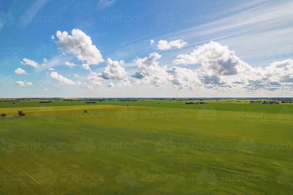 aerial shot of a big open field under cloudy blue skies - Australian Stock Image