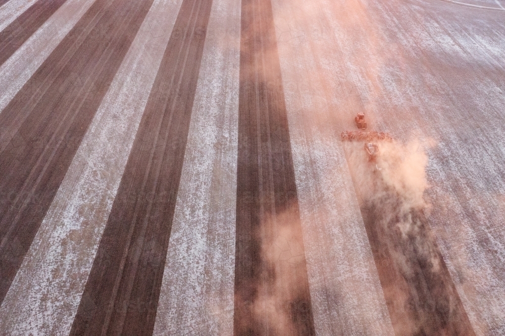 Aerial shot of dusty paddock being seeded at sunset - Australian Stock Image