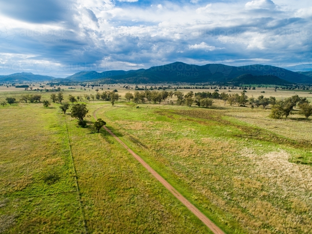 Aerial view down long farm driveway in good season with green paddocks - Australian Stock Image