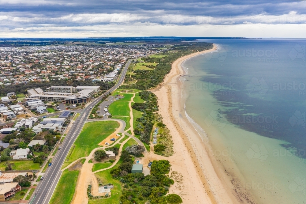 Aerial view looking along a a coastal reserve alongside a beach and city esplanade - Australian Stock Image