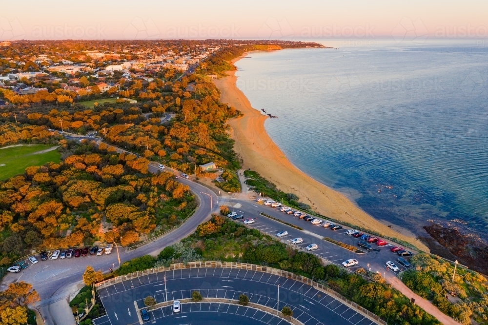 Aerial view of a bay side beach and carpark in late afternoon sunshine - Australian Stock Image