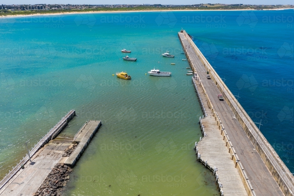 Aerial view of a boat ramp and long breakwater jutting out into a calm coastal bay - Australian Stock Image