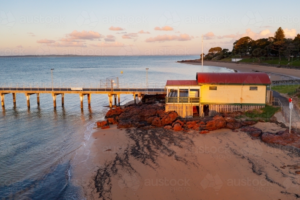 Aerial view of a boatshed at the  end of a coastal jetty in evening sunshine - Australian Stock Image