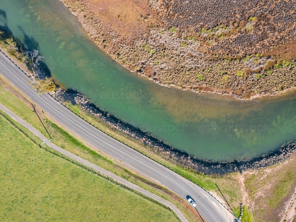 Aerial view of a car driving on a road alongside a river - Australian Stock Image