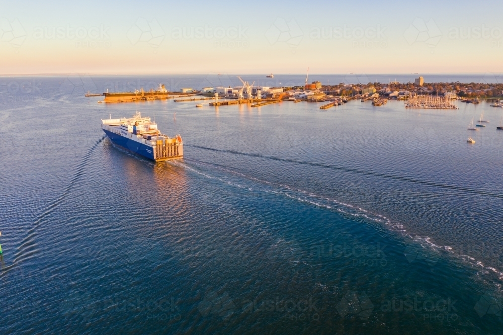 Aerial view of a cargo ship leaving a wake in calm water - Australian Stock Image