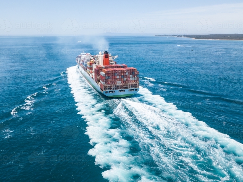 Aerial view of a cargo ship steaming through calm blue water - Australian Stock Image