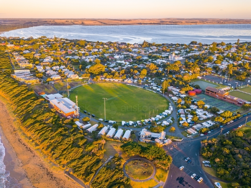 Aerial view of a coastal football oval surrounded by caravans and camp sites - Australian Stock Image