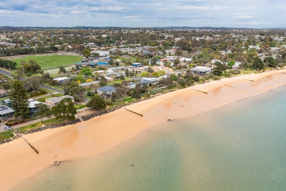 Aerial view of a coastal town and golden sandy beach with lines of groynes - Australian Stock Image