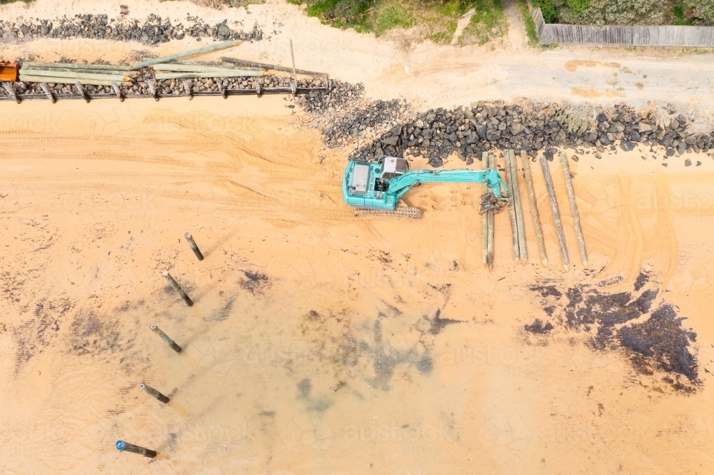 Aerial view of a colourful digger working on a sandy beach - Australian Stock Image