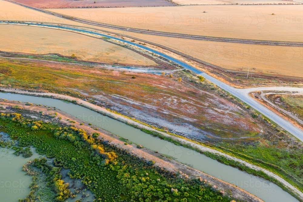 Aerial view of a country road running through farmland and next to a river - Australian Stock Image