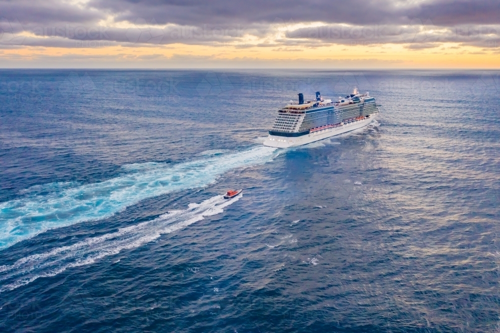 Aerial view of a cruise ship heading out to sea at sunset - Australian Stock Image