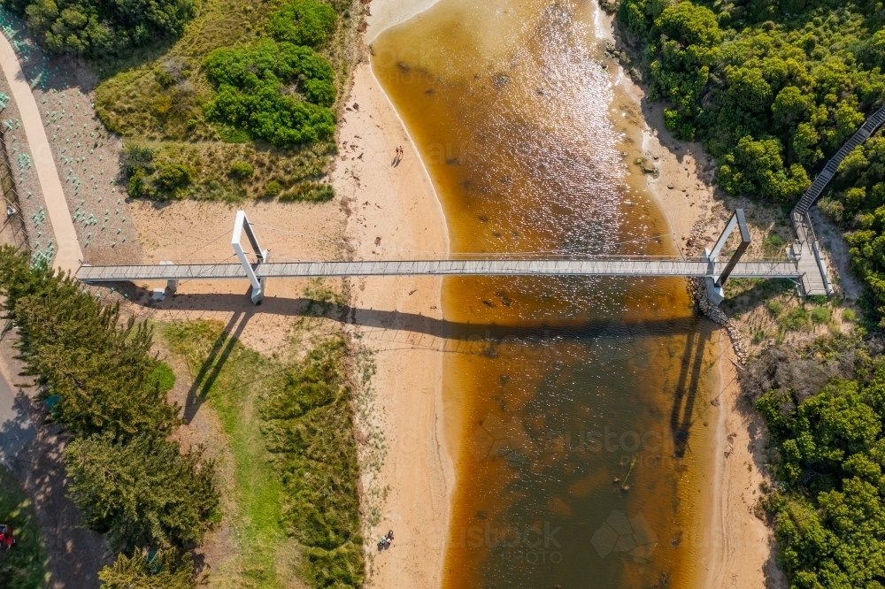 Aerial view of a footbridge over a murky river - Australian Stock Image