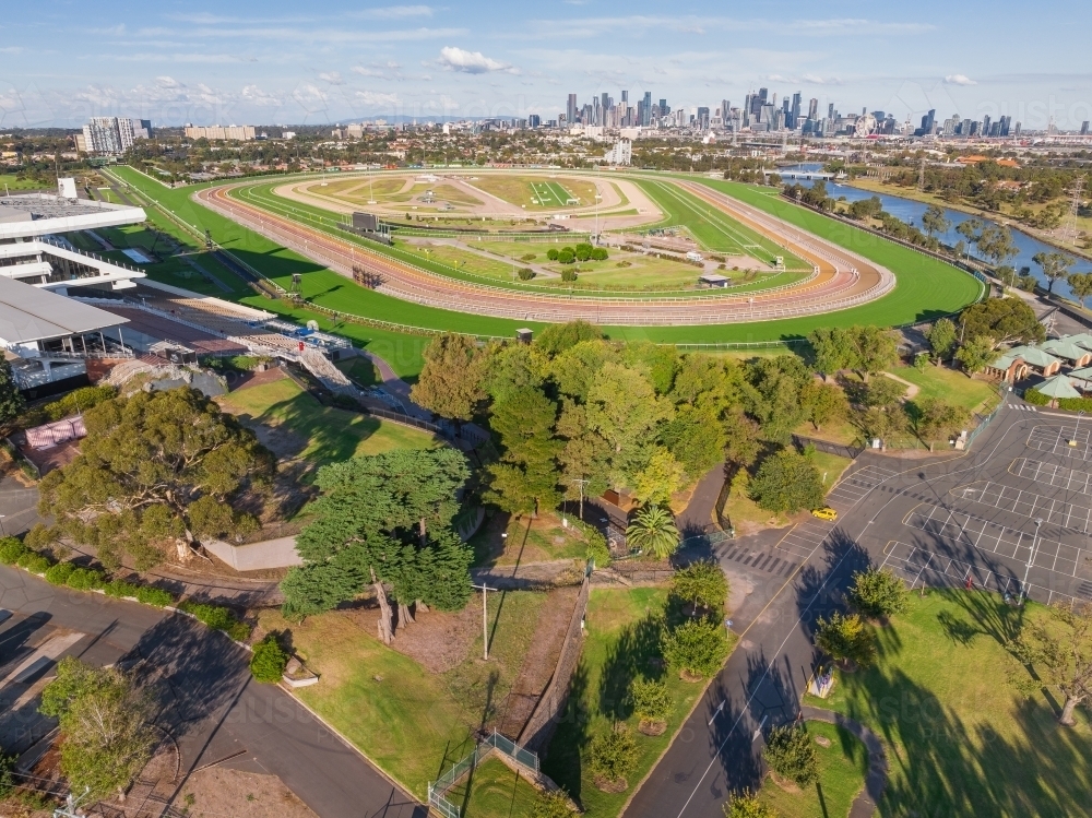 Aerial view of a horse racing track with carparking in front and a city skyline in the distance - Australian Stock Image