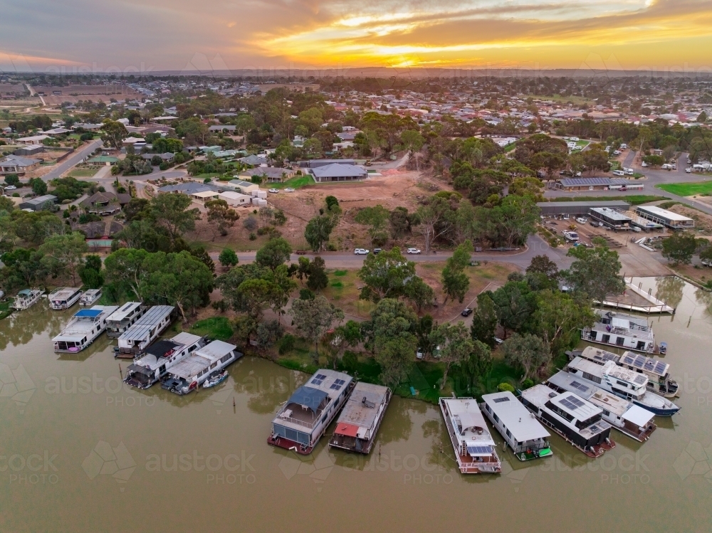 Aerial view of a house boat marina on a river with a sunset behind - Australian Stock Image