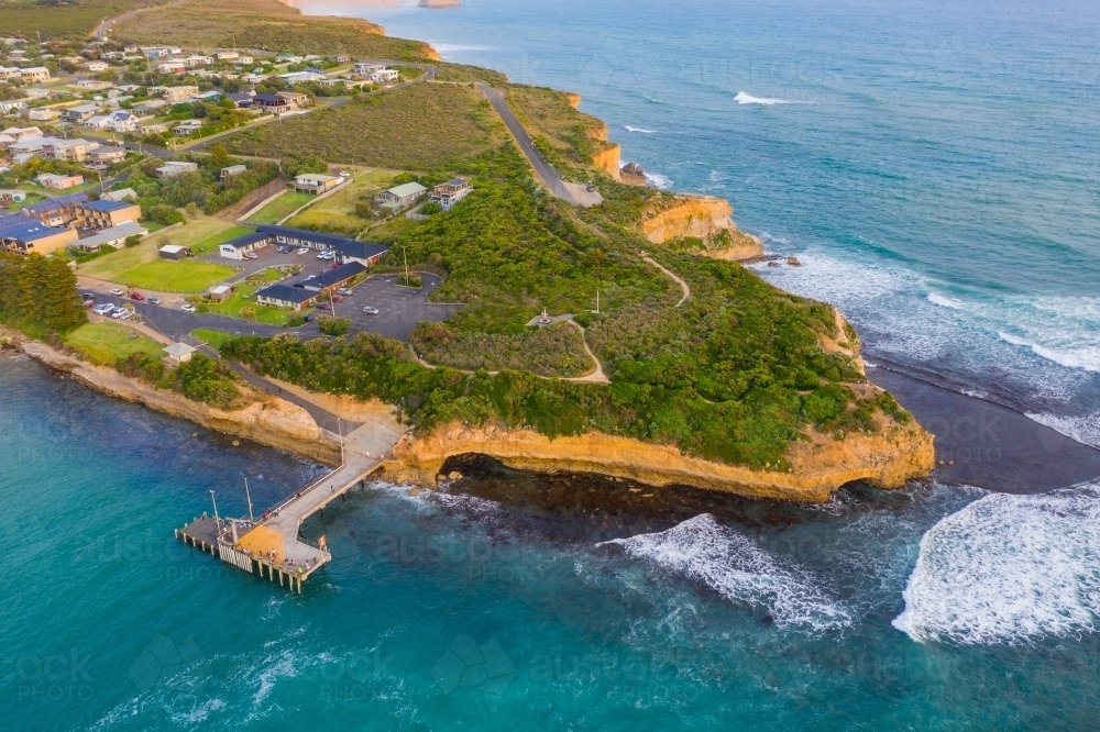 Aerial view of a jetty over deep blue water along a rugged coastline - Australian Stock Image