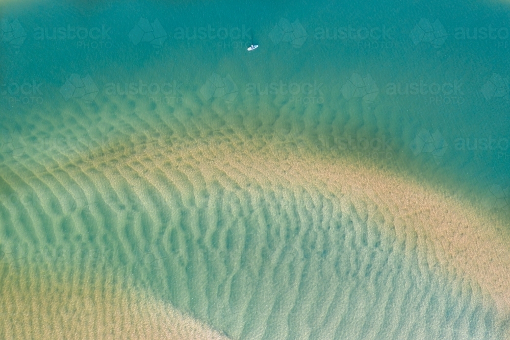 Aerial view of a kayak amongst tidal sandbars and blue water - Australian Stock Image