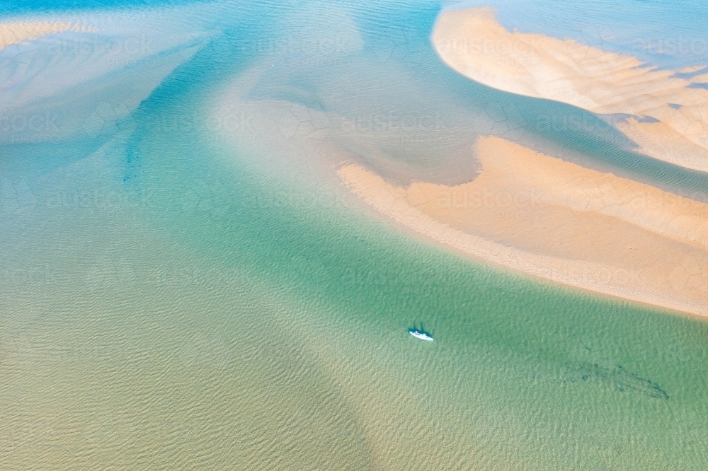 Aerial view of a kayak amongst tidal sandbars and blue water - Australian Stock Image