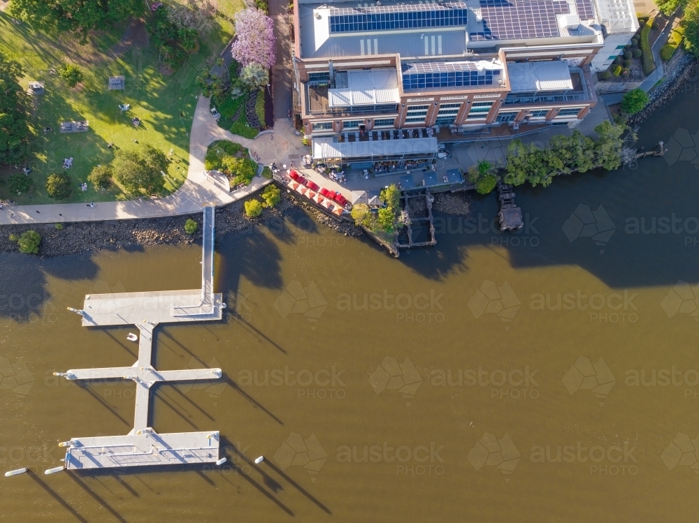 Aerial view of a large building with a jetty on the banks of a murky river - Australian Stock Image