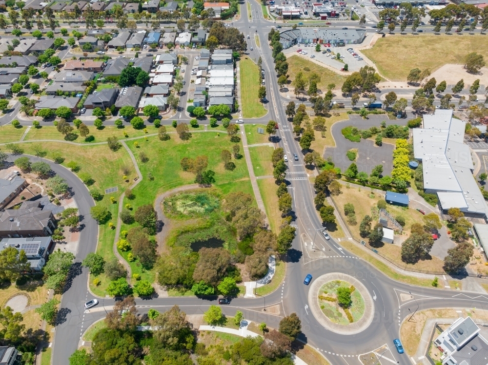 Aerial view of a large roundabout and road network through parkland and an outer city suburb - Australian Stock Image